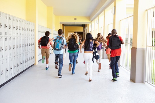 Group Of High School Students Running Along Corridor